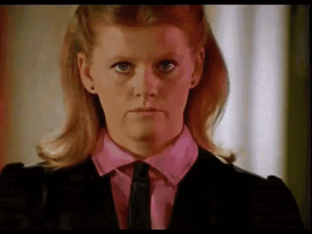 a woman wearing a pink shirt and a black tie