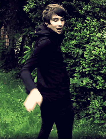 a young man in a black jacket is standing in a field