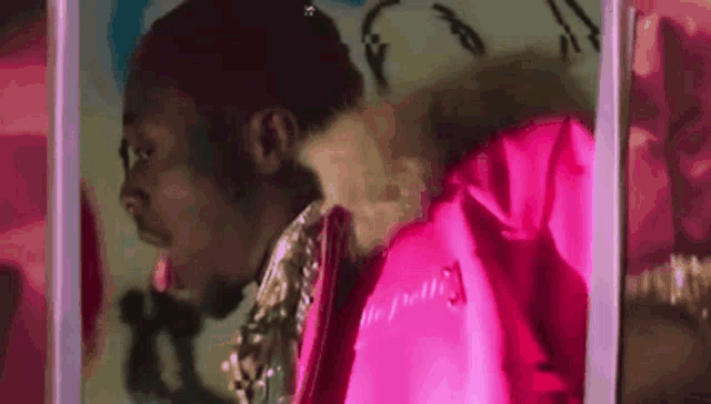 a man in a pink jacket is standing in front of a mirror .