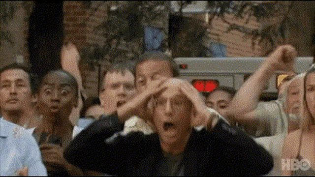 a group of people are standing in a crowd with their hands on their heads and making funny faces .