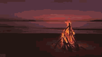 a campfire is sitting on the beach at sunset .