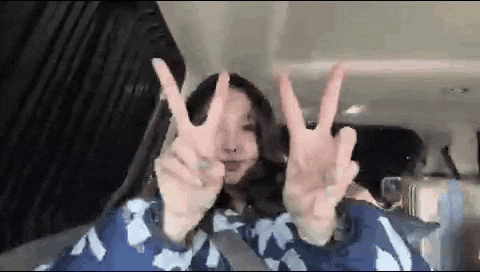a woman is giving a peace sign in a car .