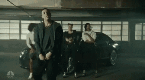 a group of people are dancing in a parking garage in front of a black car .