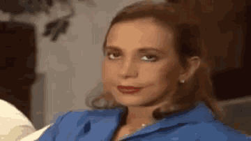 a woman in a blue shirt and red lipstick is sitting on a couch .