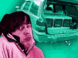 a man talking on a cell phone in front of a broken down car