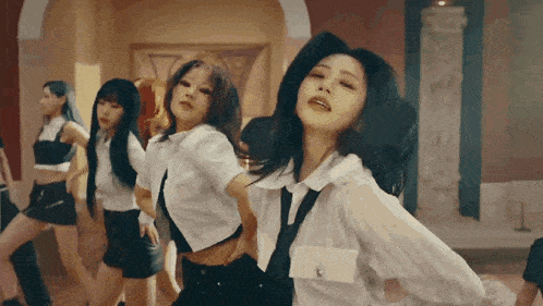 a group of women are dancing in a room with a statue in the background