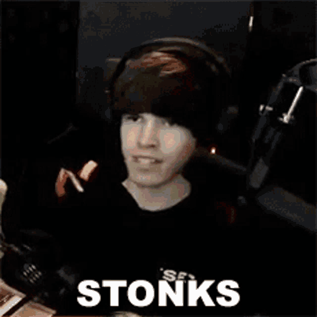 a young man wearing headphones is sitting in front of a microphone with the word stonks written on the screen .