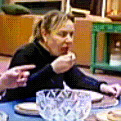 a woman is sitting at a table with plates and a bowl of food