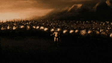 a man stands in front of a large army of soldiers with shields