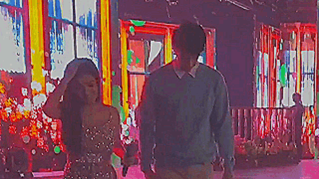 a man and a woman are standing on a stage in front of a colorful background .