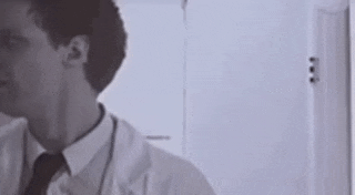 a man in a white coat and tie is standing in front of a mirror .
