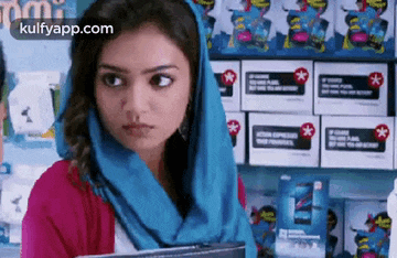 a woman with a scarf around her head is standing in front of a shelf of boxes .