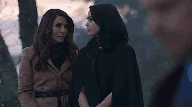 two women are standing next to each other and looking at a man