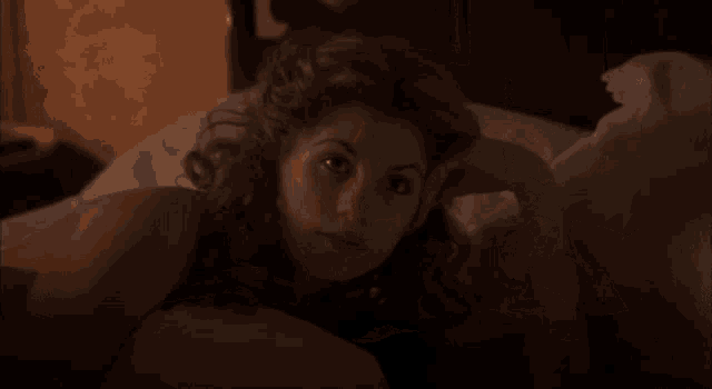 a woman is smiling while laying in a bed