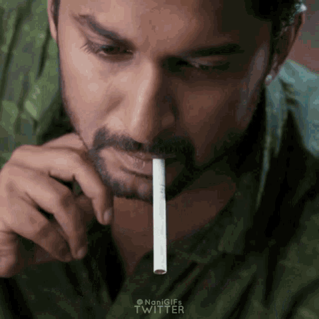a man with a cigarette sticking out of his mouth with the twitter logo on the bottom right