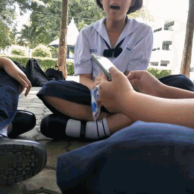 a girl sitting on the ground with a phone in her hand and a shirt that says rmj