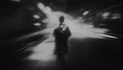 a blurry black and white photo of a person walking in a dark tunnel