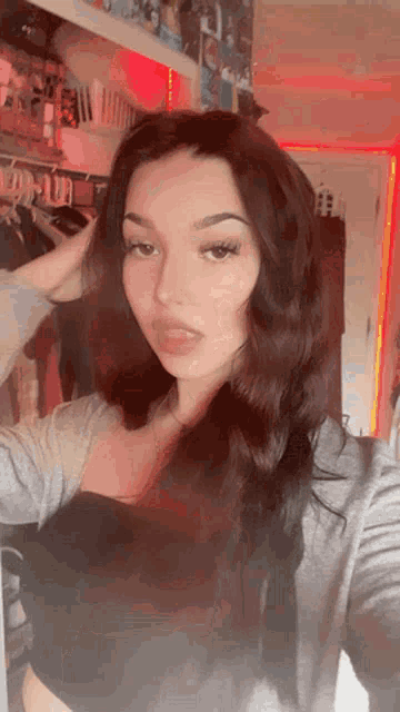 a woman is taking a selfie in front of a closet with clothes hanging on it .