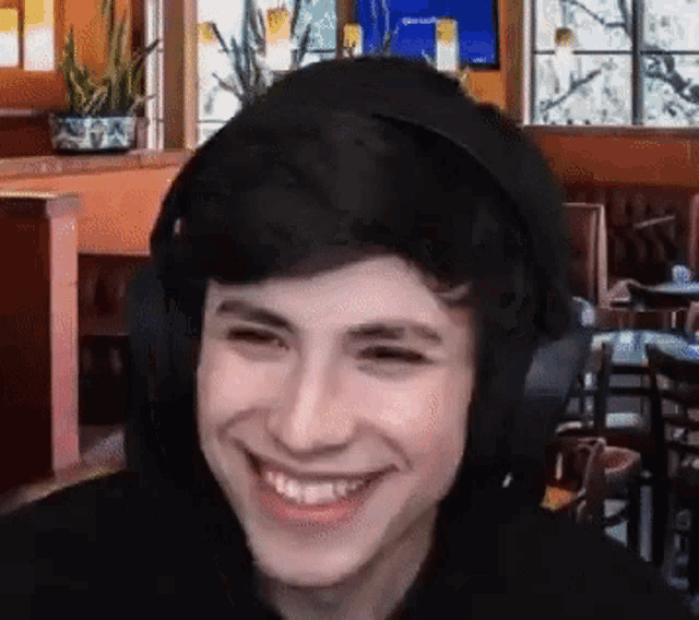 a young man wearing headphones is smiling and looking at the camera in a restaurant .