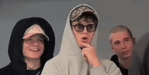 a group of young men wearing hoodies and hats are standing next to each other .