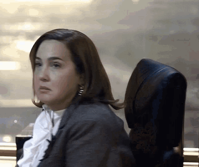 a woman sitting in a chair with earrings that say ' i ' on them