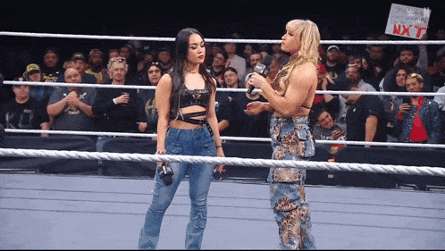 two women standing in a wrestling ring with a sign that says nxt on it