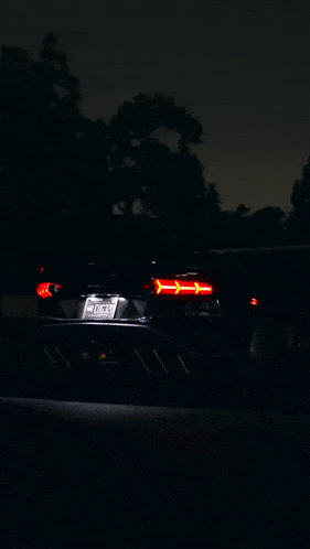 a black lamborghini is driving down a road at night with its exhaust coming out