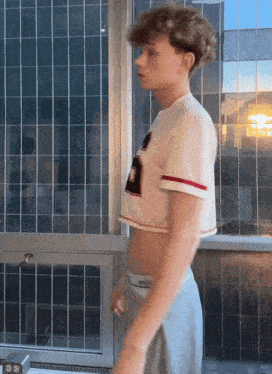 a young man wearing a crop top and calvin klein underwear stands in front of a window