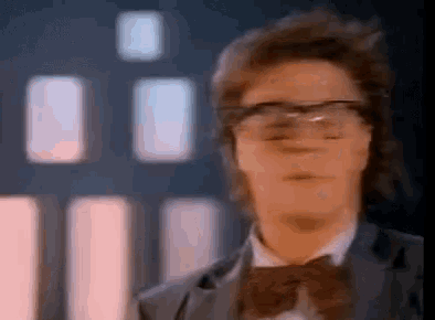 a man wearing glasses and a bow tie looks at the camera .
