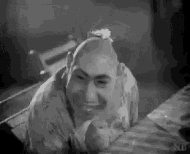 a man with a shaved head is laying on a bed and smiling .