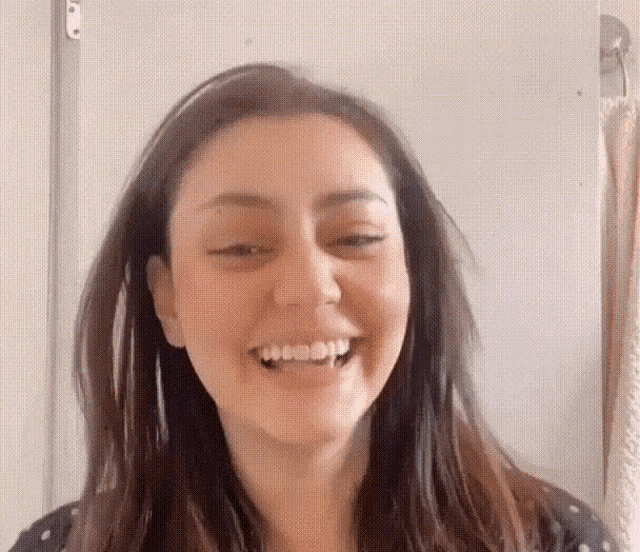 a woman with vampire teeth is smiling with her eyes closed and her mouth open .