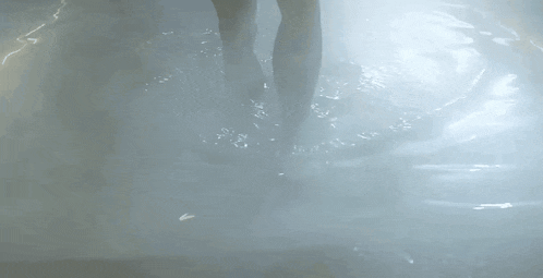 a person is walking through a pool of water in the dark .