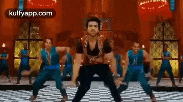 a man is dancing on a checkered floor in front of a group of people .