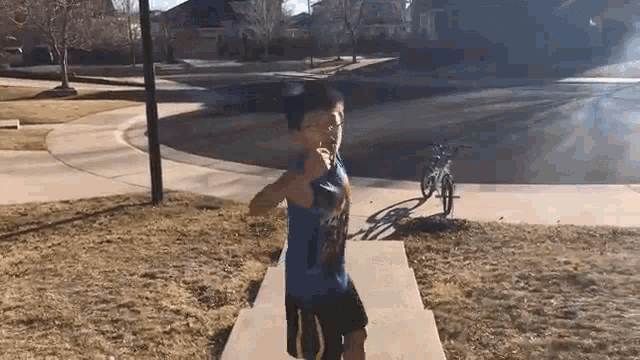 a young boy is standing on a concrete platform in a park .