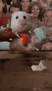 a group of people are sitting in a stadium watching a piggy bank being opened .