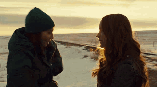 two women standing next to each other on a snowy road