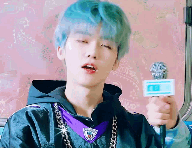 a man with blue hair is holding a microphone and wearing a nfl jersey