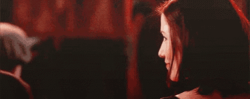 two women are looking at each other in a dark room and smiling .