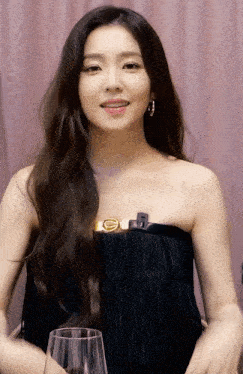 a woman wearing a black strapless dress is holding a glass of wine .