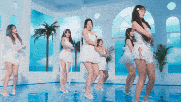 a group of women in white dresses are dancing in a room with palm trees