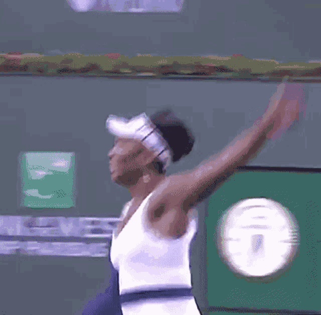 a woman in a white dress is standing on a tennis court holding a tennis racket .