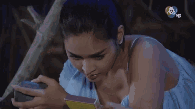 a woman in a blue dress is laying on the ground holding a box of matches .