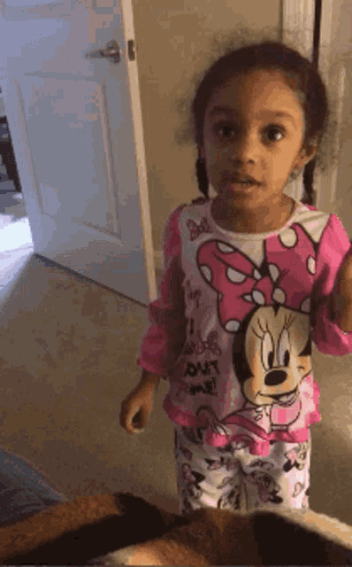 a little girl wearing a minnie mouse pajama shirt