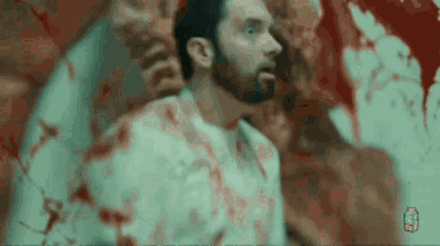 a man with a beard and a white shirt is covered in blood .