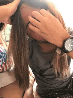 a person wearing a watch covering their face with their hand