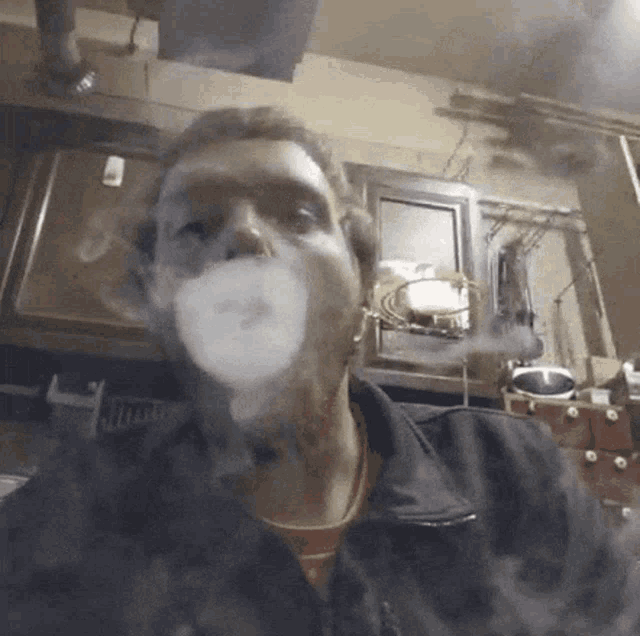 a man in a black jacket is blowing a bubble of smoke