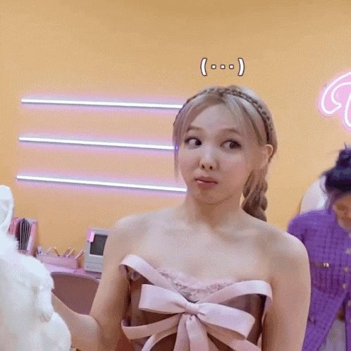 a woman in a pink strapless dress with a bow on the front is standing in a room .