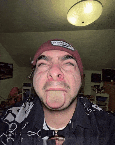 a man wearing a hat that says vans on it sticks out his tongue