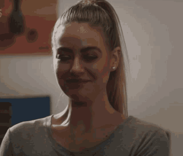 a woman with a ponytail is smiling in front of a painting