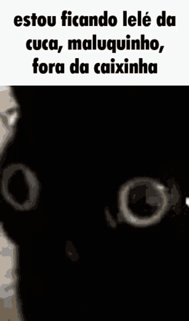 a black cat is looking at the camera with a white hand behind it .